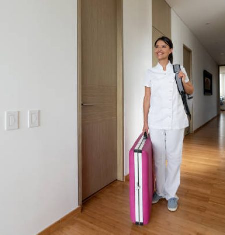 Happy Latin American masseuse arriving at a client's house with her equipment and smiling - beauty concepts